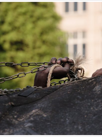 Migrant's or refugee's hand in chains in a European city square.