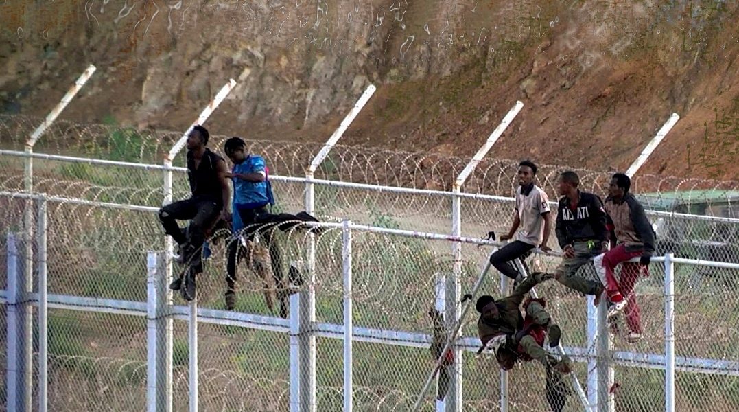 A symbol of illegal migration in Spain: Illegal migrants sitting on top of the fence on the Spanish-Moroccan border.