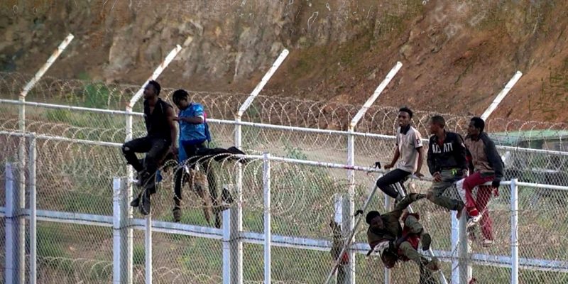 A symbol of illegal migration in Spain: Illegal migrants sitting on top of the fence on the Spanish-Moroccan border.
