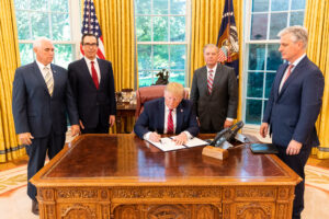 President Donald J. Trump, joined by Vice President Mike Pence, Secretary of the Treasury Steven Mnuchin, National Security Advisor Robert O'Brien, and Sen. Lindsey Graham, signs an Executive Order, 2019. Photo source: Official White House Photo / Shealah Craighead / Trump White House Archived / Flickr, Public Domain Mark