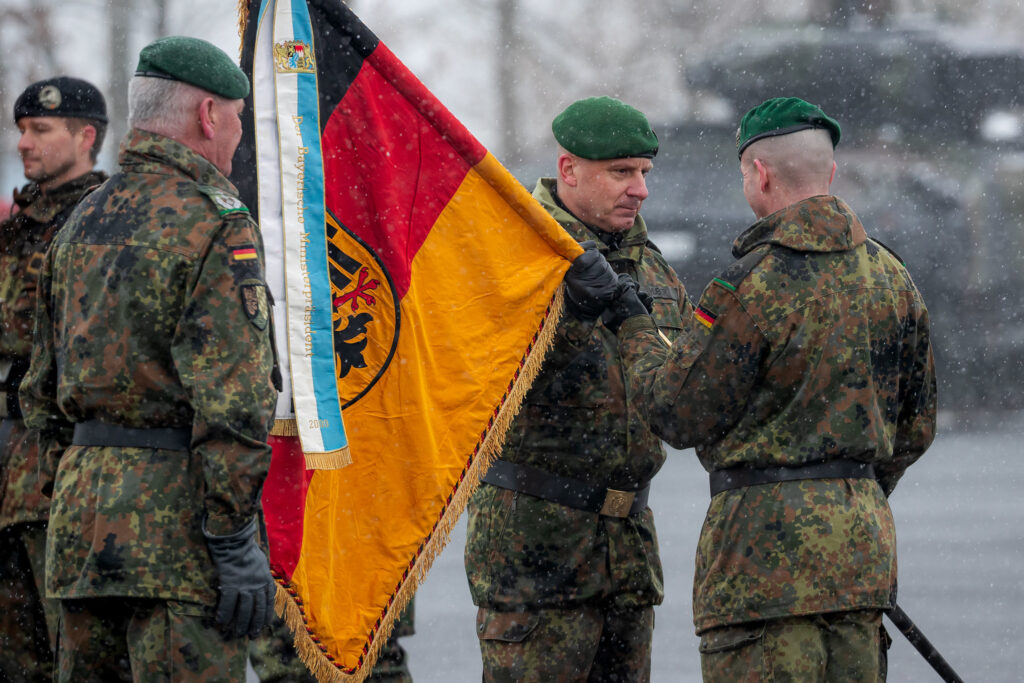 Brigadier General Christoph Huber (mi), Commander of Panzer Brigade 45 "Lithuania", hands over the troop flag of Panzergrenadier Battalion 122 to its commander, Lieutenant Colonel Rayk Engel (re), at the roll call of the combat troop battalions Panzergrenadier Battalion 122 and Panzer Battalion 203 to Panzer Brigade 45 "Lithuania" in Veitshöchheim, on January 29, 2026 (Photo: Bundeswehr/Marco Dorow/Flickr.com)